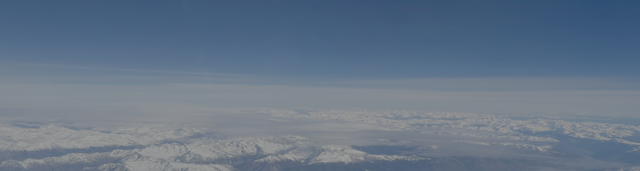 Home page header image of snow covered mountains with low aerosol and clouds in sky.